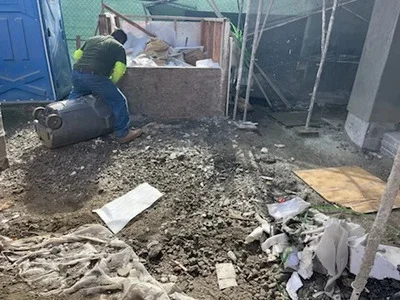 Worker removing concrete rubble and construction debris from commercial site with hauling equipment