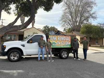 Junk removal team loading items into hauling truck at residential property