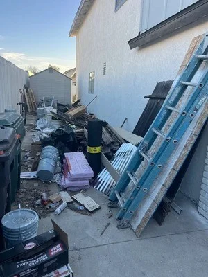 Pile of residential junk including appliances, metal materials, and household items staged for removal