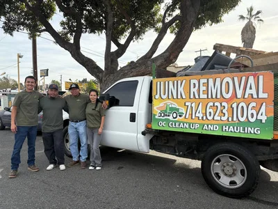 Junk removal team standing beside white pickup truck with company branding and hauling equipment