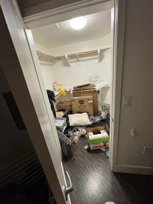 Before photo of cluttered bedroom with boxes, furniture, and miscellaneous items removed during junk hauling service