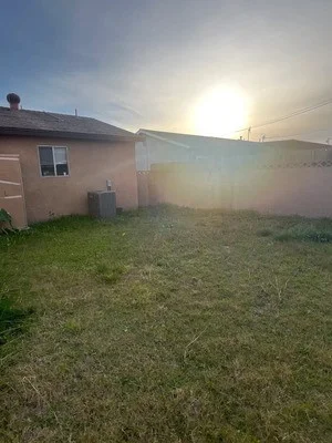 Cleared residential yard with pink house and metal structure removed, clean grass area