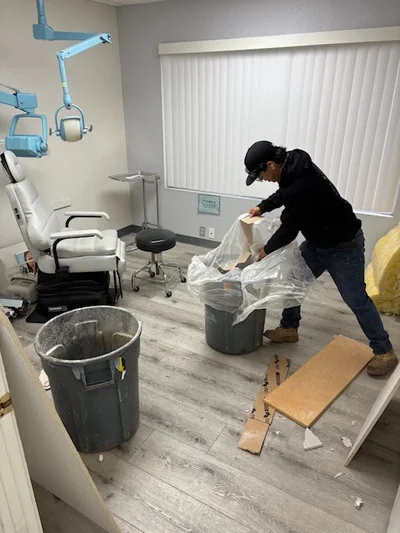 Worker removing medical office equipment and debris into industrial waste containers