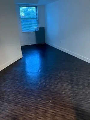 Empty commercial room with dark concrete floor, white walls, and window after junk removal