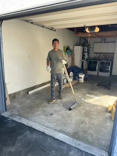 Worker removing junk and debris from garage interior with concrete floor