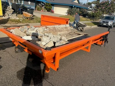 Orange flatbed trailer loaded with concrete chunks and construction debris