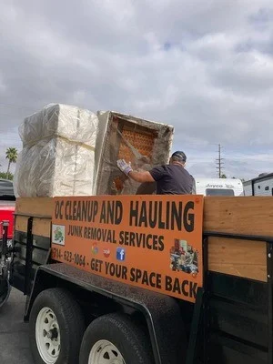 Open-bed hauling truck with wooden rails loaded with mixed junk and debris for removal