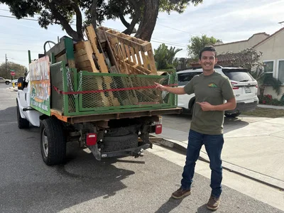 Loaded hauling truck with wood pallets, lumber, and mixed residential junk ready for removal
