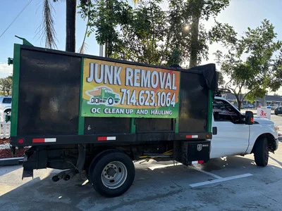 Green and black enclosed dump truck with hydraulic lift system for junk removal services