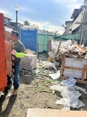 Worker removing construction debris and mixed waste from commercial property with hauling equipment