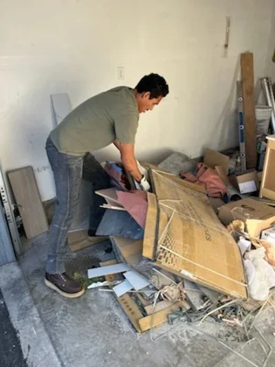 Worker loading cardboard boxes and household debris into hauling vehicle