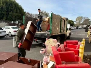 Junk removal crew loading furniture and household items onto hauling truck