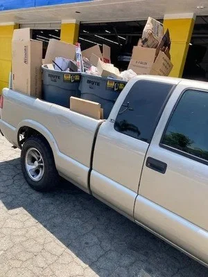 White pickup truck loaded with cardboard boxes and household junk items ready for hauling