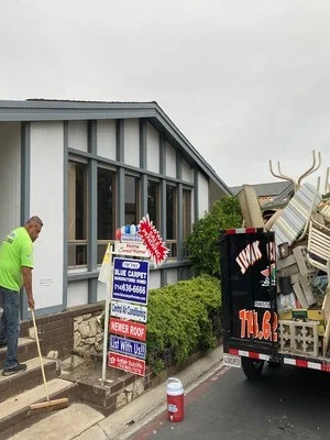 Junk removal truck loading mixed commercial debris from storefront property